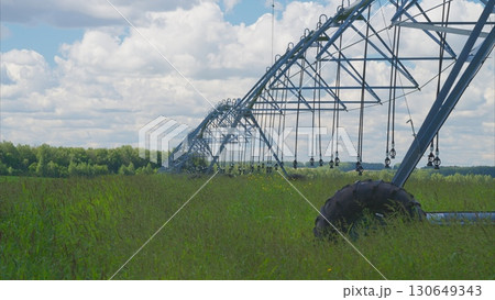 Irrigation System Set Up in a Vibrant Green Field Beneath a Cloudy Sky with Beauty 130649343