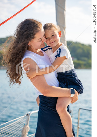 Mother and daughter spending time together on the bow of a sailing yacht. Family bonding, sea adventure, and peaceful travel lifestyle 130649714