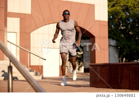 Man running outdoors in athletic gear with urban architecture background Man running outdoors in athletic gear with urban architecture background 130649881