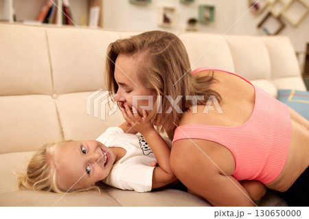 Mother and child sharing playful moments together on the living room couch 130650000