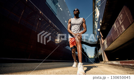 Athlete stretching outdoors in an urban setting before a workout Athlete stretching outdoors in an urban setting before a workout 130650045