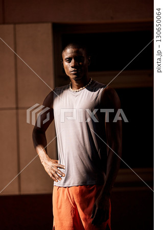 Young athlete wearing a sleeveless shirt posing confidently in natural light 130650064