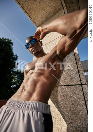 Muscular man posing outdoors in athletic wear under natural sunlight Muscular man posing outdoors in athletic wear under natural sunlight 130650149