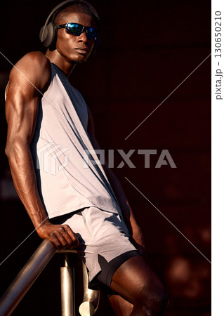 Athletic man outdoors wearing headphones and sunglasses in sporty attire 130650210
