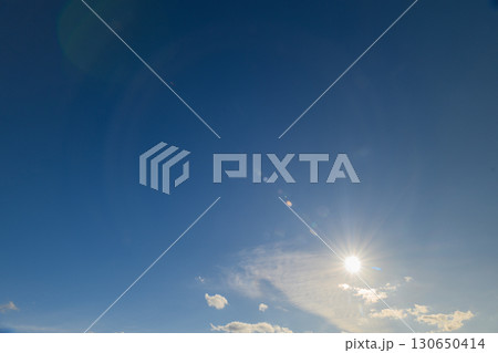 A beautiful clear blue sky with bright sunshine and several fluffy clouds drifting gracefully A beautiful clear blue sky with bright sunshine and several fluffy clouds drifting gracefully 130650414