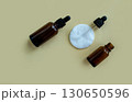 Flat lay vials with a pipette and a white cotton pad on a beige background. 130650596