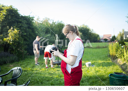 Pregnant woman in garden looking at camera screen outdoors Pregnant woman in garden looking at camera screen outdoors 130650607