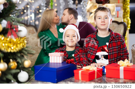 Children and parents give each other gift boxes during Christmas or New Year celebrations at home 130650922