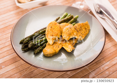 fried chicken breast pieces with asparagus on plate 130650923