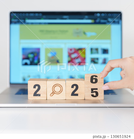2025 end year to Happy New Year 2026 block magnifying glass icon against laptop background. Hiring, recruitment, job, jobless SEO, Search Engine Optimization and New Year concepts 130651924