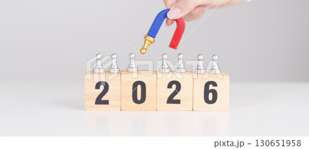 hand holding magnet and pulling man chess figure from the crowd employee with 2026 Year block. Human resource management, Recruitment, Teamwork, strategy, toxic people and leadership Concepts hand holding magnet and pulling man chess figure from the crowd employee with 2026 Year block. Human resource management, Recruitment, Teamwork, strategy, toxic people and leadership Concepts 130651958