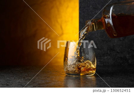 Pouring whiskey from a bottle into a glass. Pouring whiskey from a bottle into a glass. 130652451