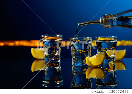 Vodka and lemon slices on a dark blue background. Vodka and lemon slices on a dark blue background. 130652481