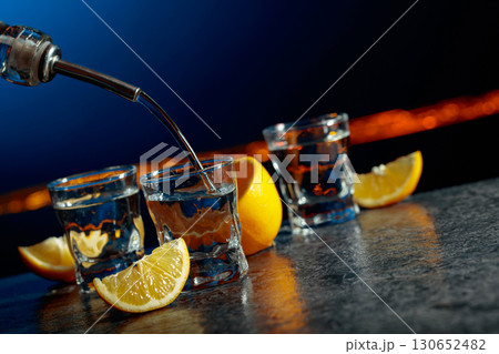 Vodka and lemon slices on a dark blue background. Vodka and lemon slices on a dark blue background. 130652482