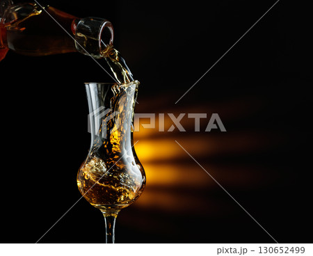 Rum being poured from a bottle into a glass. 130652499
