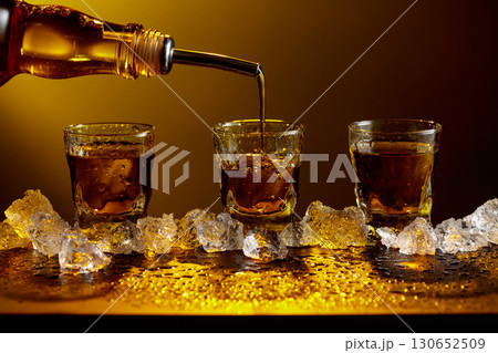 Whiskey pours from bottle to glass. 130652509