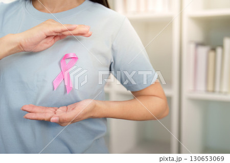 Breast Cancer Awareness. Woman holding pink ribbon symbol with care. 130653069