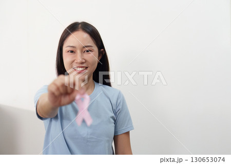 Breast Cancer Awareness. Smiling woman showing pink ribbon. 130653074