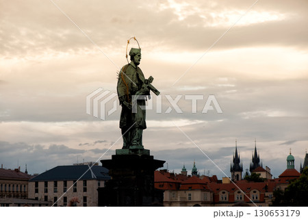Bronze statue of St. John of Nepomuk on Charles Bridge with Prague's skyline in the backdrop, Czech Republic 130653179