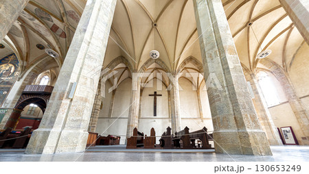 Inside a Emmaus Monastery featuring towering stone columns and an arched ceiling 130653249