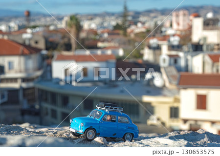 Miniature blue car exploring a blurred cityscape 130653575