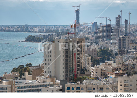 Construction cranes building modern buildings in city by the sea on sunny day Construction cranes building modern buildings in city by the sea on sunny day 130653657