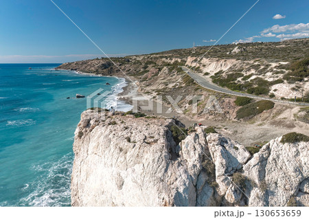 Tourists admiring the turquoise sea from Aphrodite's rock on a sunny day. Paphos District, Cyprus Tourists admiring the turquoise sea from Aphrodite's rock on a sunny day. Paphos District, Cyprus 130653659