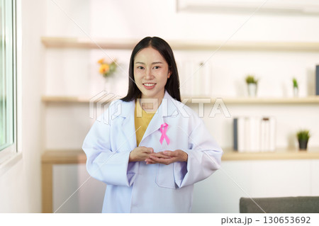 Breast Cancer Awareness. Smiling healthcare worker presenting pink ribbon. Breast Cancer Awareness. Smiling healthcare worker presenting pink ribbon. 130653692