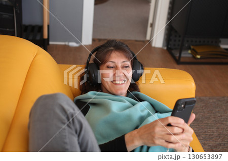 an adult woman listening music at her home in headphones, lifestyle people 130653897