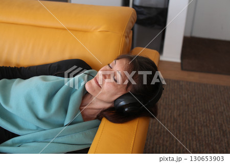 an adult woman listening music at her home in headphones, lifestyle people an adult woman listening music at her home in headphones, lifestyle people 130653903