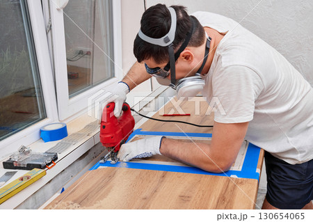 repairman using electric jigsaw and cutting hole for the sink in the kitchen countertops, Woodworking and carpentry concept 130654065