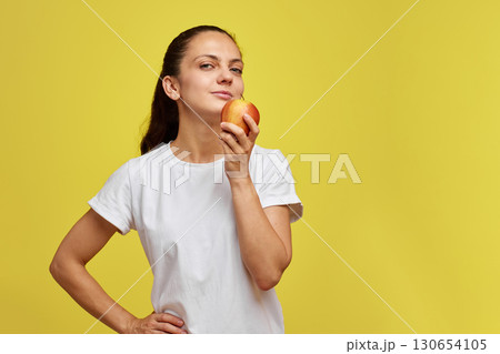 Portrait of happy woman holding apple isolated over yellow background Portrait of happy woman holding apple isolated over yellow background 130654105