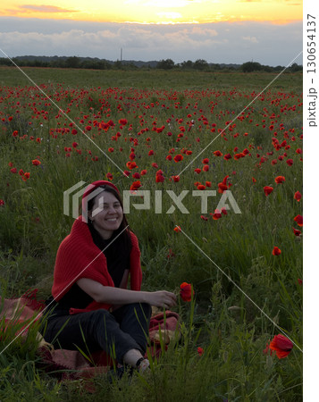 Young Woman in Poppy Field with Red Hat 130654137