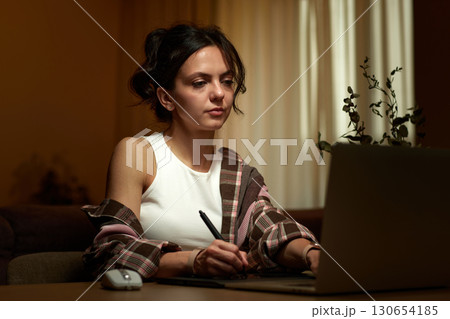 beautiful professional female retoucher woman working at home workspace using digital graphic tablet with stylus and laptop, post production software on graphic tablet. 130654185