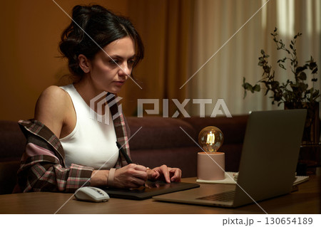 beautiful graphic designer woman working at home office remotely using digital graphic tablet and laptop 130654189
