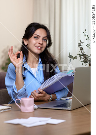 Happy woman showing ok gesture while study online on a laptop at home. Lady recommending online education Happy woman showing ok gesture while study online on a laptop at home. Lady recommending online education 130654198
