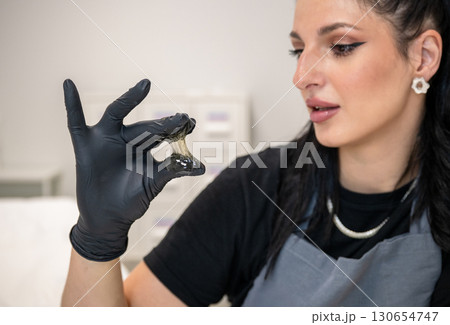 Beautician woman in black gloves holding sugaring paste for professional hair removal 130654747