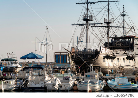 Large black pirate ship docked next to small white boats in Ayia Napa, Cyprus 130654796