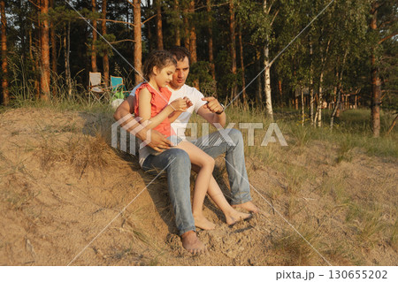 Dad explains something to his daughter outdoors in sunset on beach Dad explains something to his daughter outdoors in sunset on beach 130655202