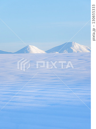 青空と十勝岳連峰を望む北海道美瑛町の冬の雪原風景 130655333