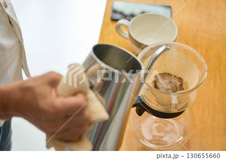 1回目の蒸らしの湯を注ぐ男性。ペーパードリップでコーヒーを淹れる工程の連続写真。 130655660