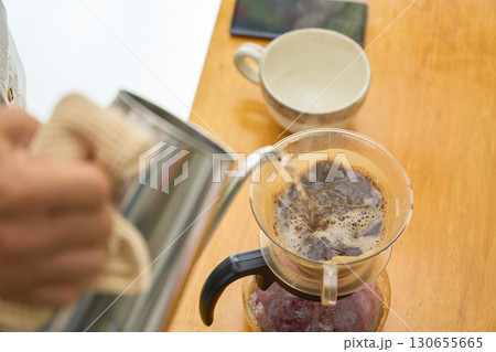 2回目3回目の抽出用の湯を注ぐ男性。ペーパードリップでコーヒーを淹れる工程の連続写真。 130655665