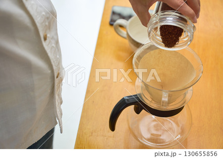 ドリッパーに中細挽きの豆の粉を入れる男性。ドリップコーヒーを淹れる工程の連続写真 130655856