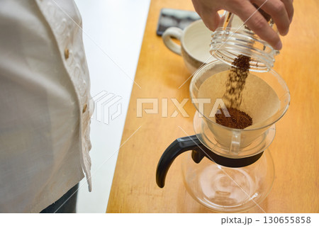 ドリッパーに中細挽きの豆の粉を入れる男性。ドリップコーヒーを淹れる工程の連続写真 130655858