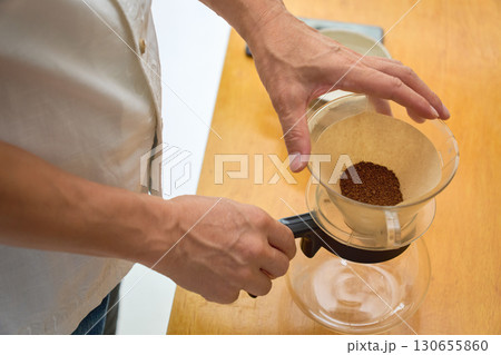 ドリッパーに中細挽きの豆の粉を入れる男性。ドリップコーヒーを淹れる工程の連続写真 130655860