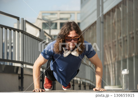 Sporty man or athlete does push ups and workout in public park. Outdoors training. Morning routine. Summer workout. 130655915