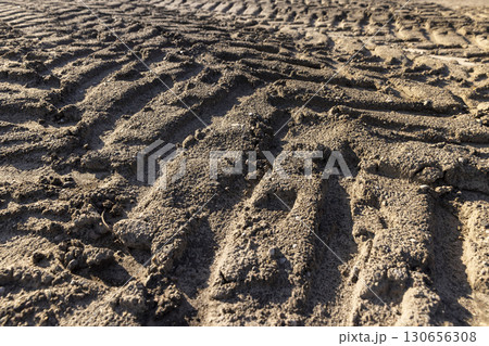 car tracks on the soil in the field, tracks from the large tread of very heavy vehicles in the field after harvesting 130656308
