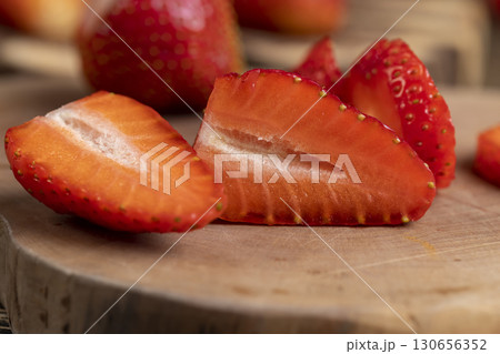 several sliced red ripe strawberries, ripe sweet and juicy strawberries cut into pieces on a wooden table 130656352