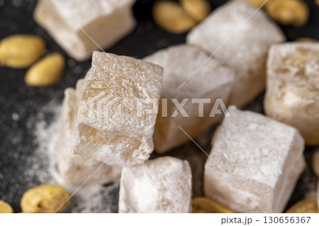 Turkish delight cubes and toasted peanuts on a black slate surface, closeup 130656367