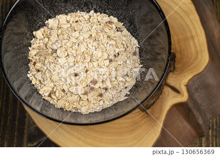 black bowl of oatmeal porridge with dried berries and fruits, filled with instant oatmeal porridge with additives, close up 130656369